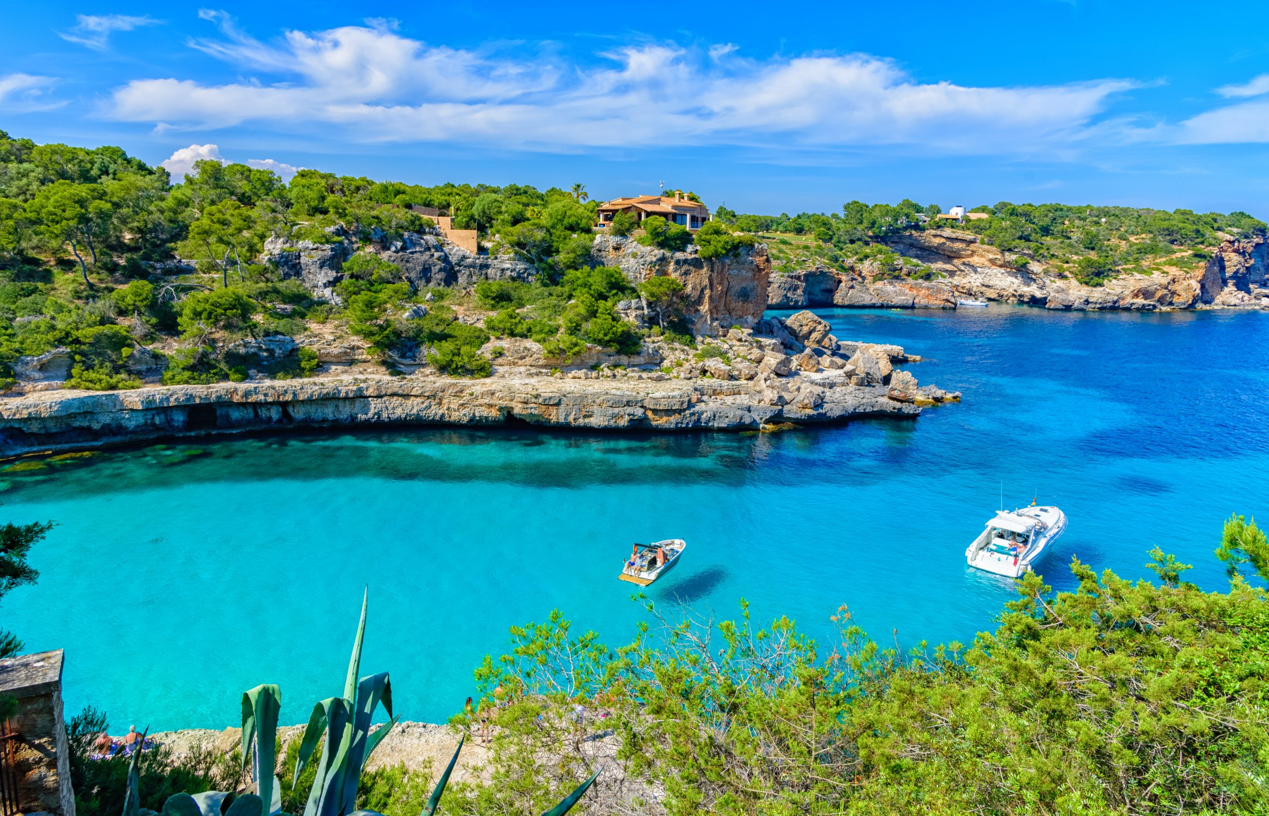 Summer holiday scene with boats on turquoise sea water of Mallorca in Cala Llombards beach, Palma de Mallorca in Spain